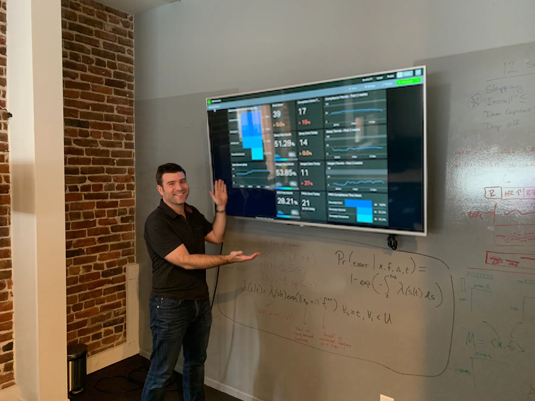 Customer presenting a Geckoboard dashboard on a wall-mounted TV during an office visit.