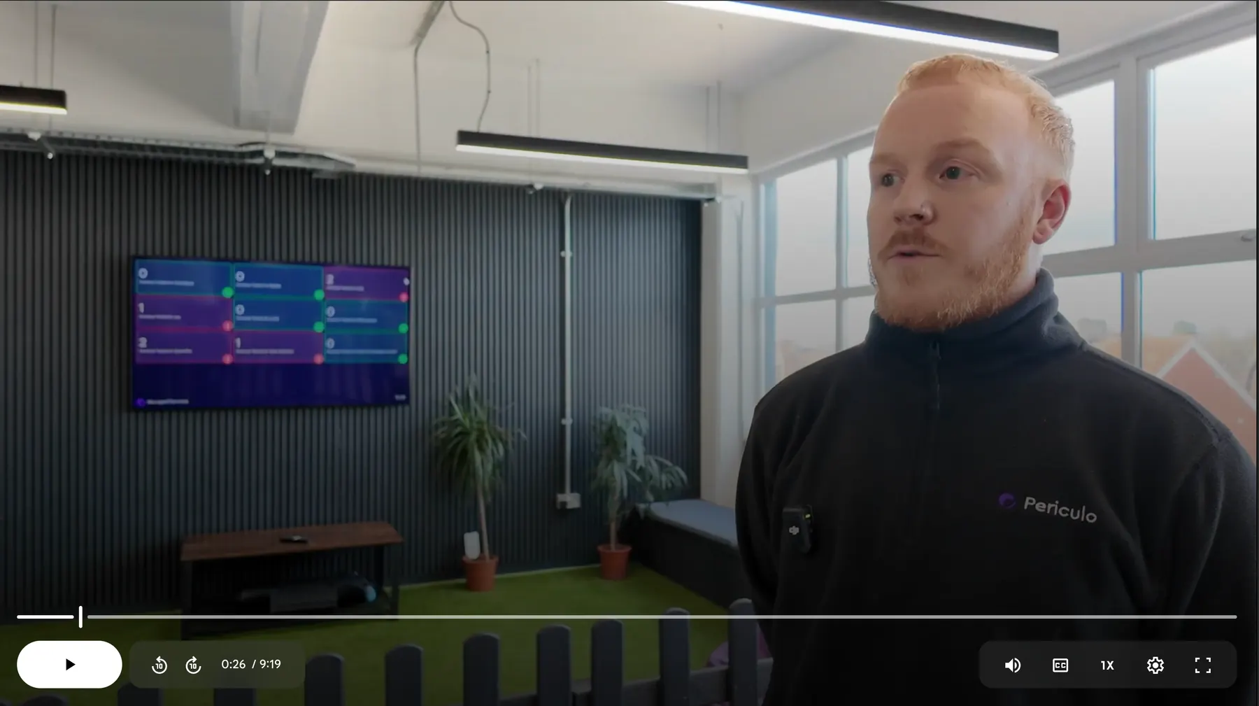 Periculo customer video still showing a dashboard on a workplace TV and an interview subject.