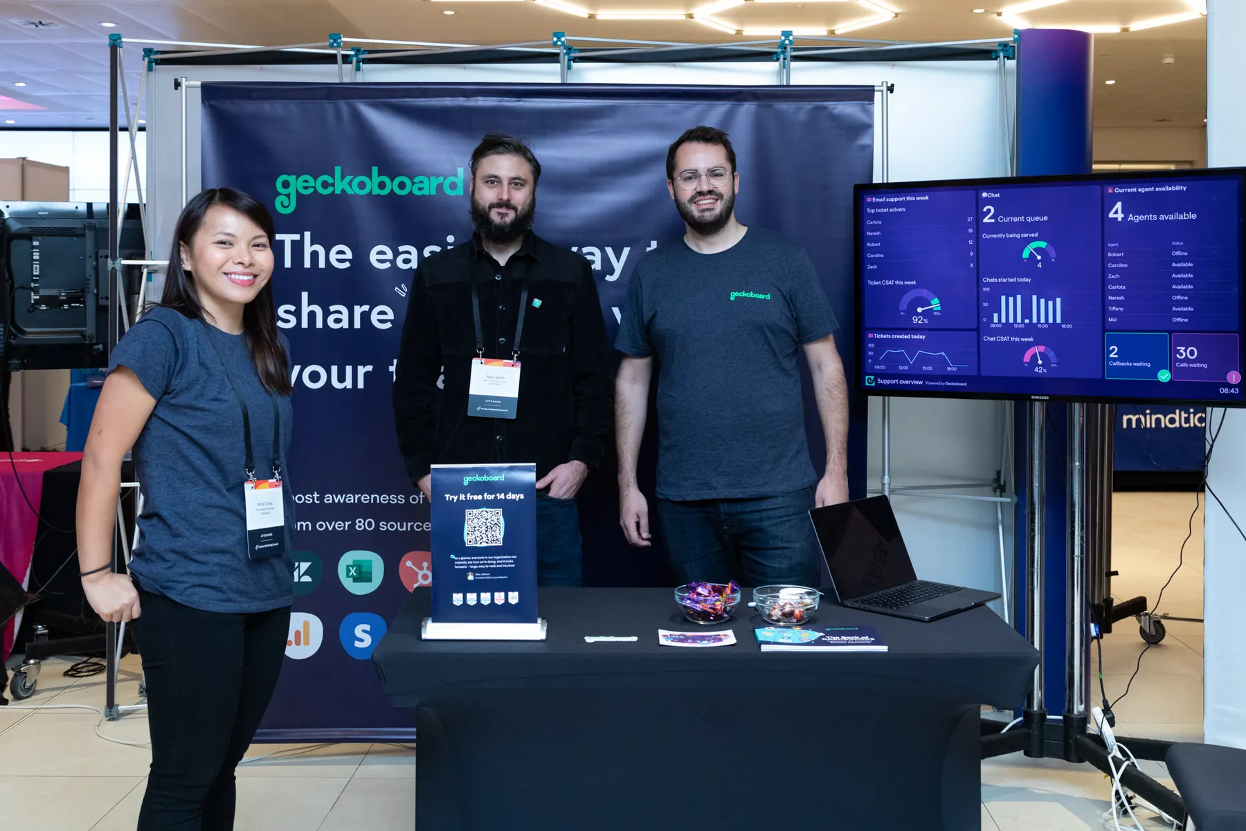 Geckoboard event stand with team, banner, TV dashboard demo, and collateral at an Alliance event in London.