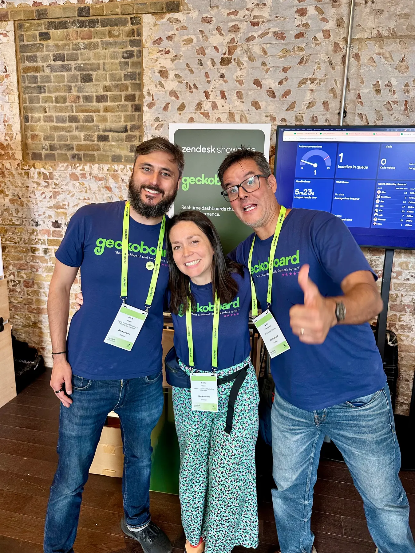 Geckoboard team at a Zendesk Showcase stand with branded shirts and a TV dashboard demo.